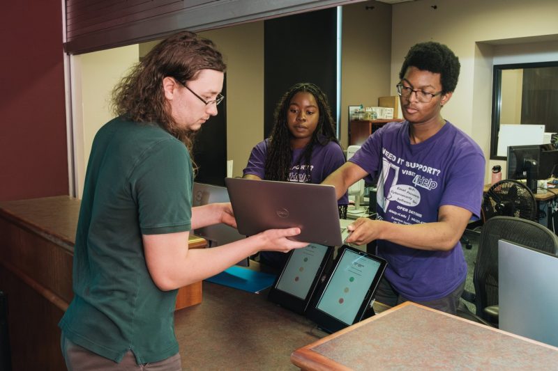 student receives help with his computer from I.T. support staff